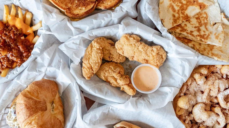 Various snacks with sauce on paper, top view