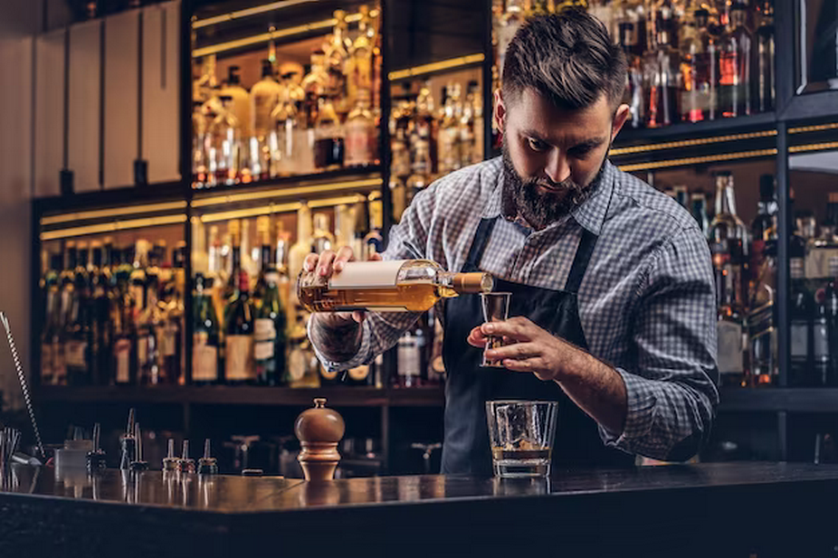 Bartender pours whiskey into a measuring glass